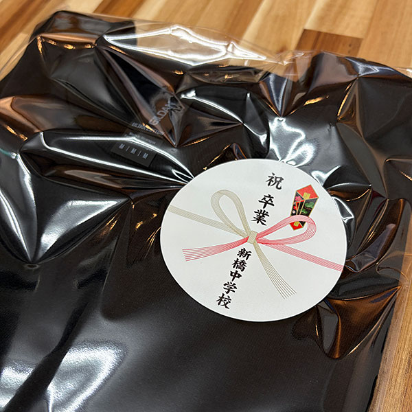 制作事例 熨斗(のし)シール:W80×H80mm　袋の中でずれてしまいがちな衣類には熨斗シールがおすすめです。卒園や卒業記念品用にどうぞ!